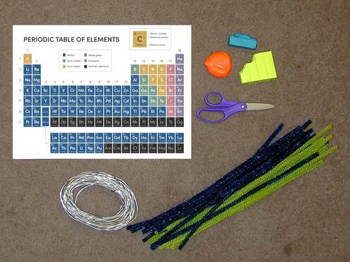 periodic table printout, wire, pipe cleaners, a scissors, orange clay, blue clay, yellow clay