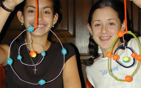 two girls holding up the atomic mobiles they made