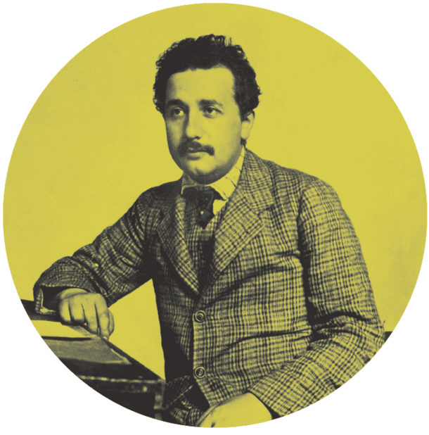 Einstein as a young man in a suit seated at a desk.