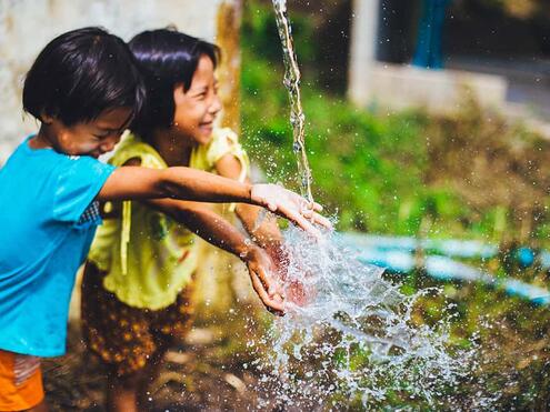 two girls outside playing with running water