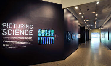A title graphic for Picturing Science is displayed in a long hallway