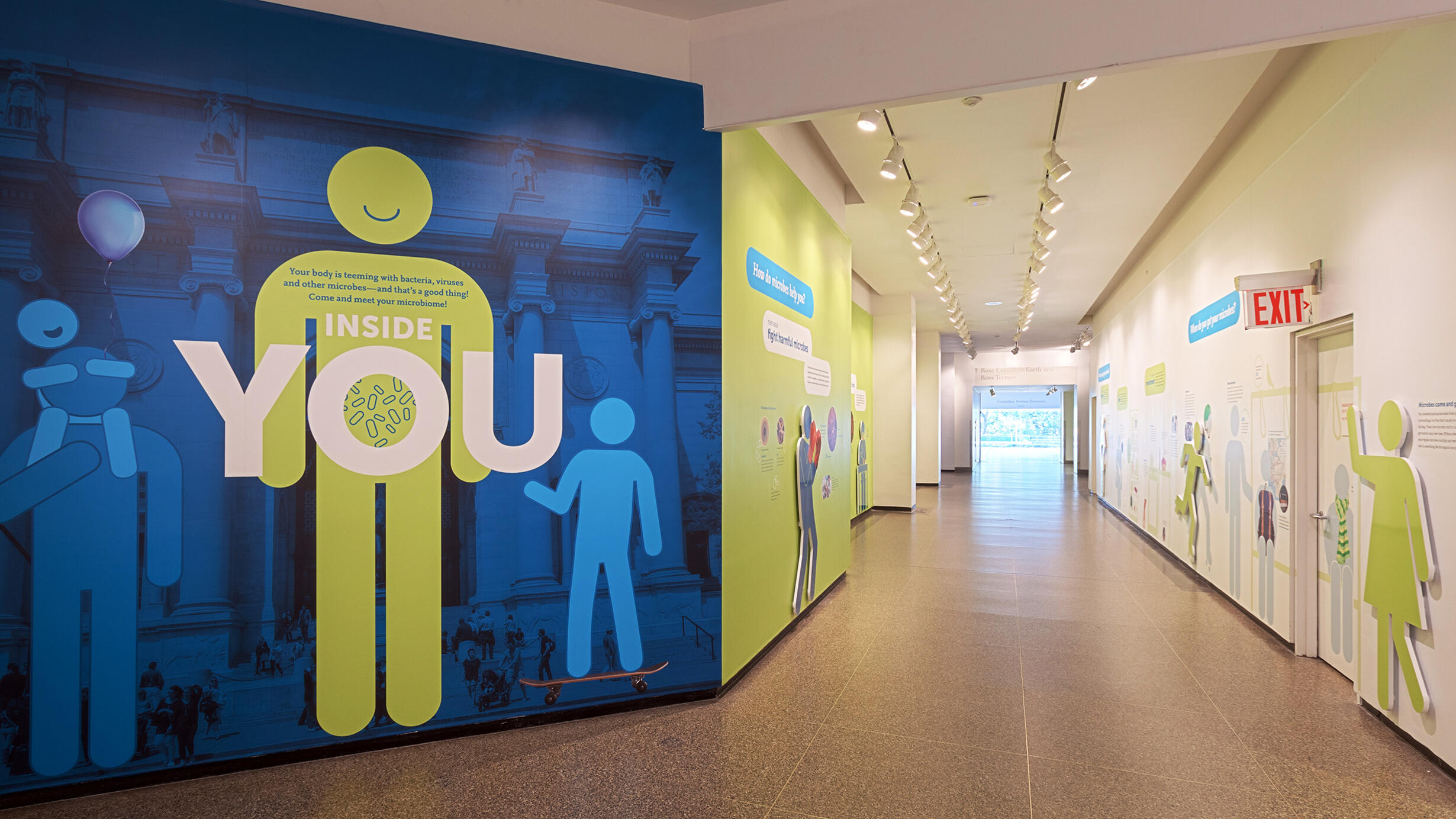 A long hallway is decorated with colorful graphics and text with cutouts shaped like humans