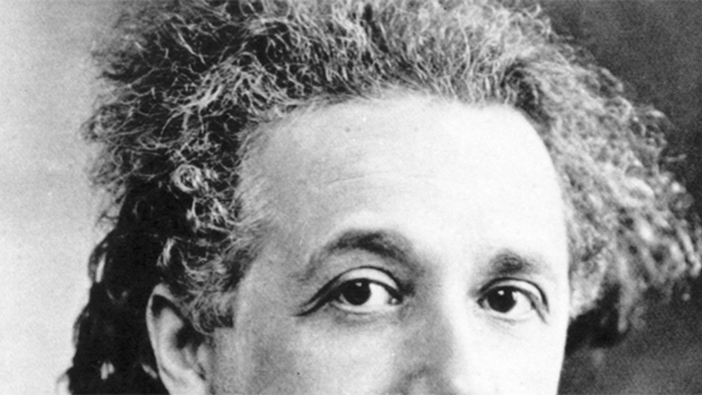 A greyscale photograph of Albert Einstein, cropped to only show his eyes, forehead, and his iconic wild hair.