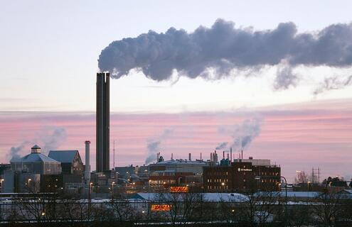 A factory with prominent chimneys emitting smoke into the atmosphere