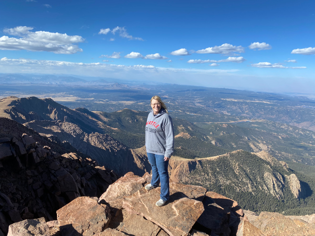 photo of Amie Thompson standing atop a mountain