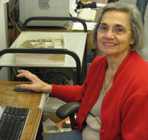 A woman smiling at the camera and seated at a desk.