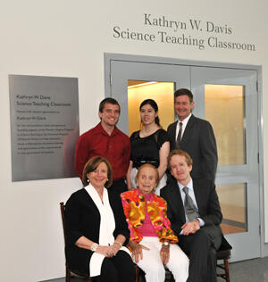 Six people posing outside a door above which are the words: "Kathryn W. Davis Science Teaching Classroom."