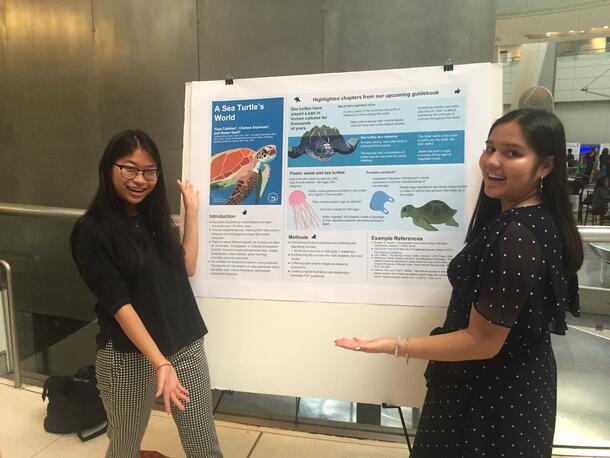 Two students stand by their turtle poster preparing to present their research. 