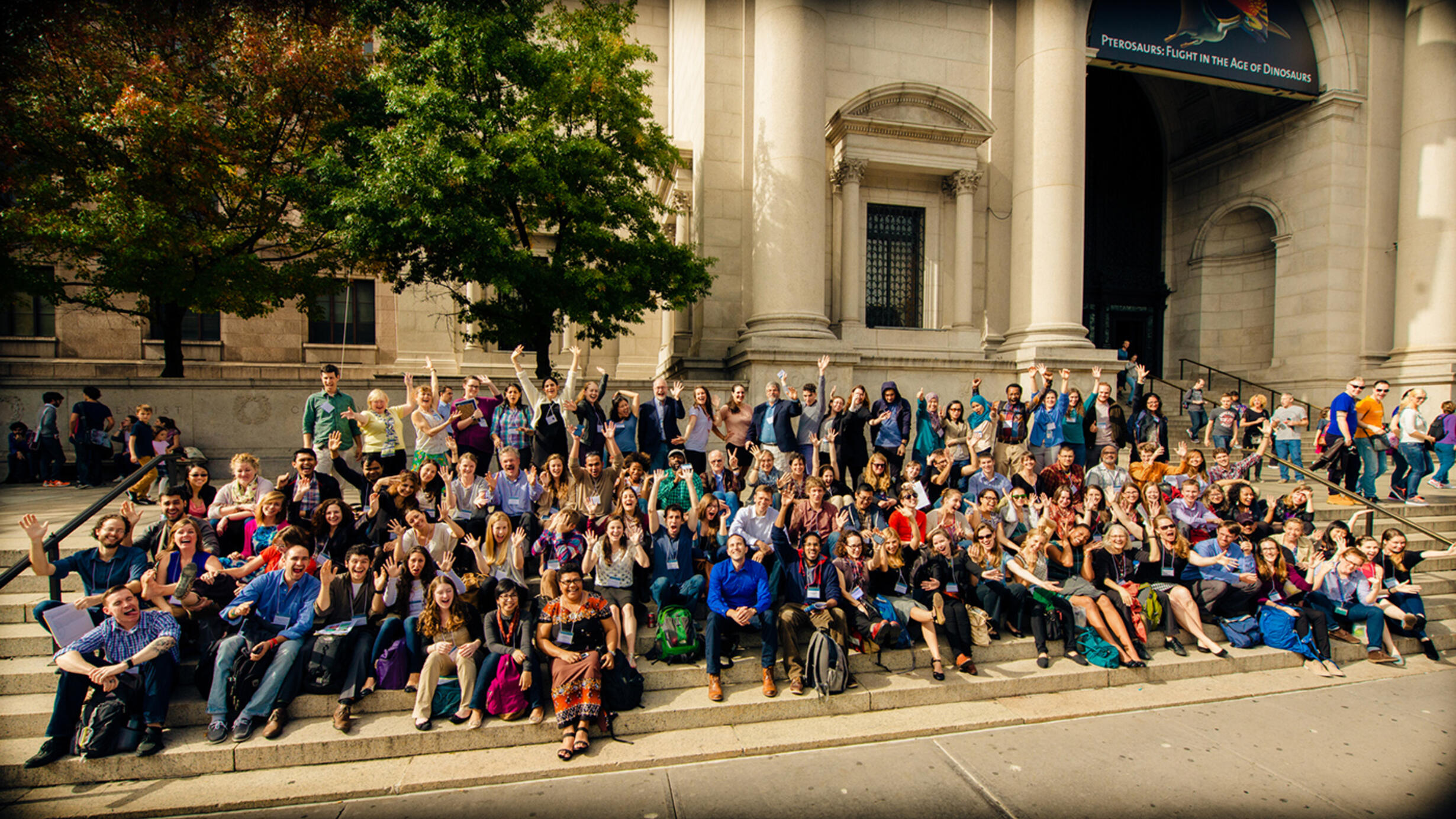 Group photo with about 100 people seated in rows or standing on the steps of the Museum's Central Park West entrance.