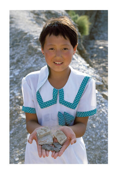 Child holds two fossil specimens in their outstretched hands.