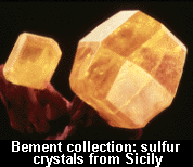 Two crystals, cut with facets, with a caption superimposed at the bottom of the photo stating: "Bement collection: sulfur crystals from Sicily."
