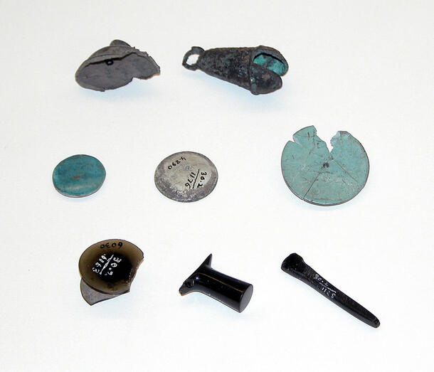 Eight small objects including a pendant and several small discs.