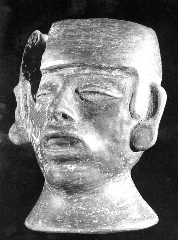 An effigy jar, sculpted in the detailed likeness of a human face with the neck forming the base of the vessel.