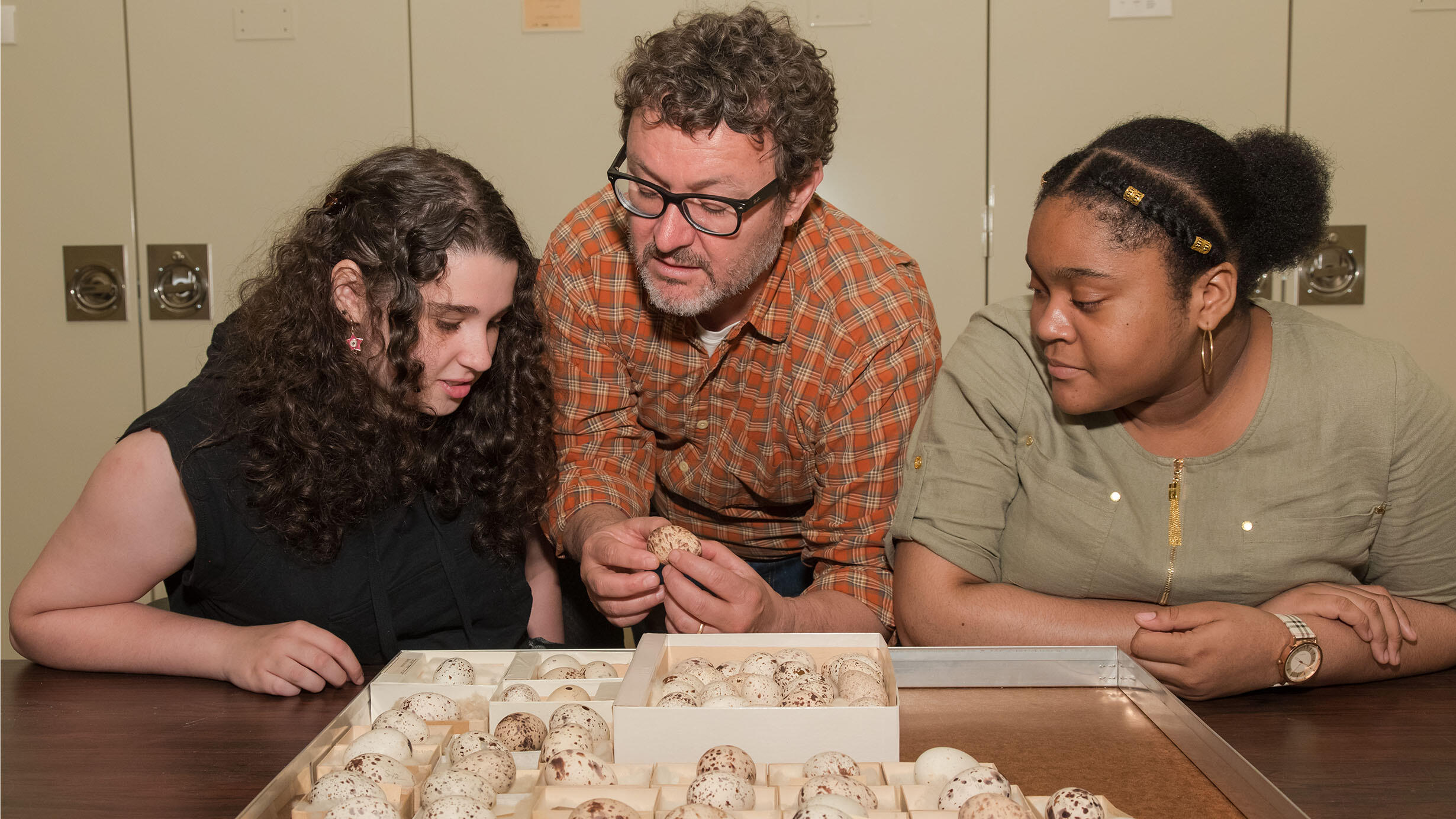 A SRMP instructor and two students examine egg specimens on a table.