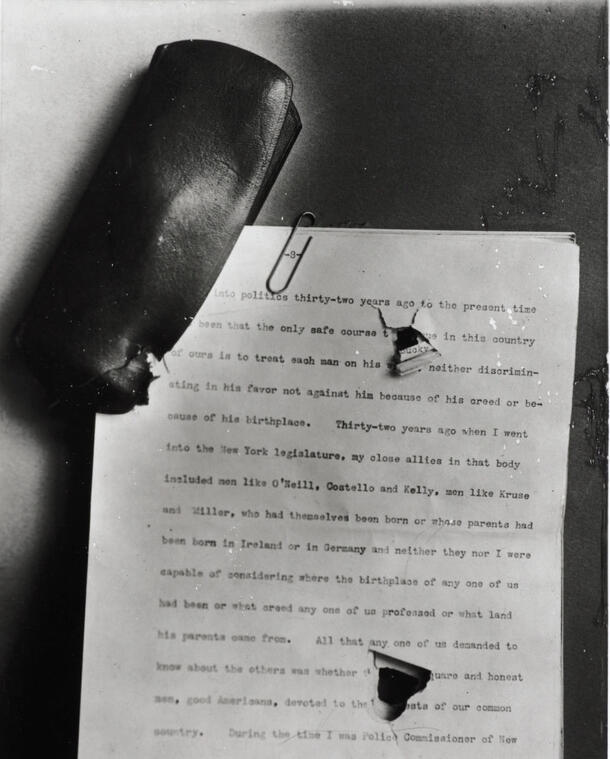 A copy of Theodore Roosevelt's typed speech, held together with a paper clip, with two holes in it and a damaged glasses case. 