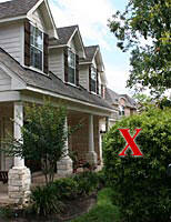 Photo of wood-frame house with dormer windows and and porch pillars. Red X on nearby tree locates mockingbird nest.