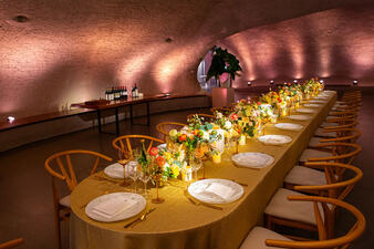 A long table that seats approximately 20 is set with flowers, glassware and tableware in one of the cave-like spaces inside the Museum's Richard Gilder Center.
