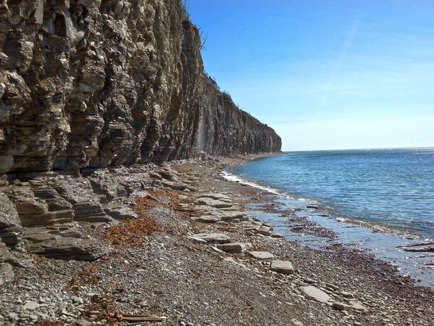 A rock face rises above a narrow strip of rocky beach on Anticosti Island, in the Gulf of Saint Lawrence in eastern Quebec.