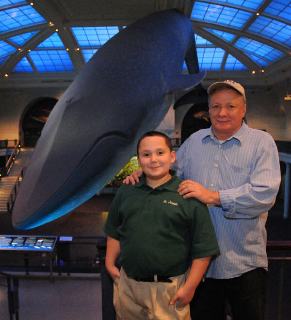 A man and a boy, Gregory Cox and grandson Shane, standing on the upper level of the Museum’s Hall of Ocean Life. The Blue Whale is in the background.