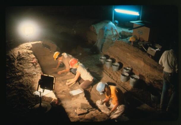 Archeologists working at night on a dig with equipment and lights