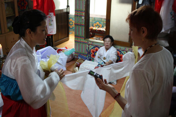 Three women in a room with ceremonial furnishings, two in perhaps ceremonial attire.