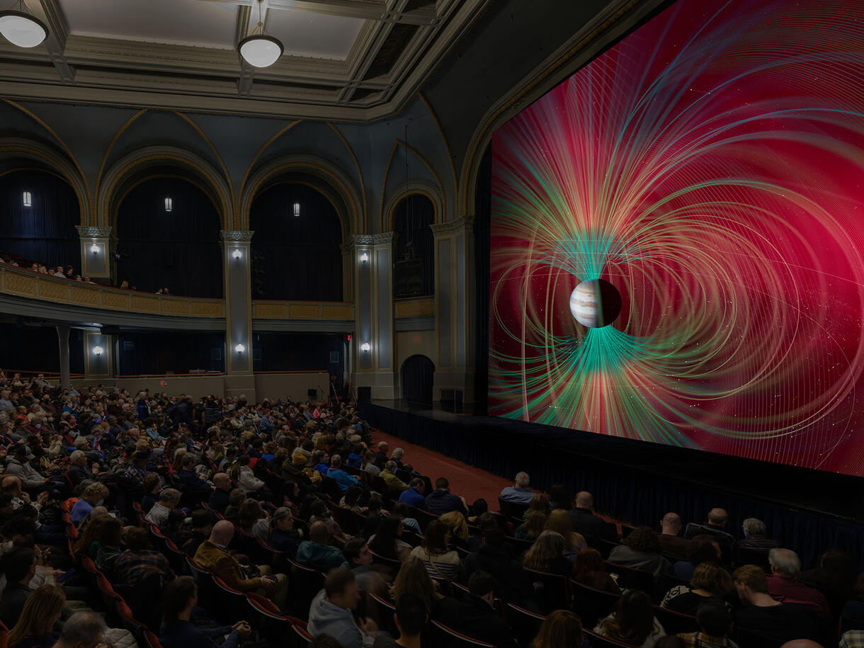 Seated audience views images of space on a giant screen inside the Museum's Lefrak Theater.