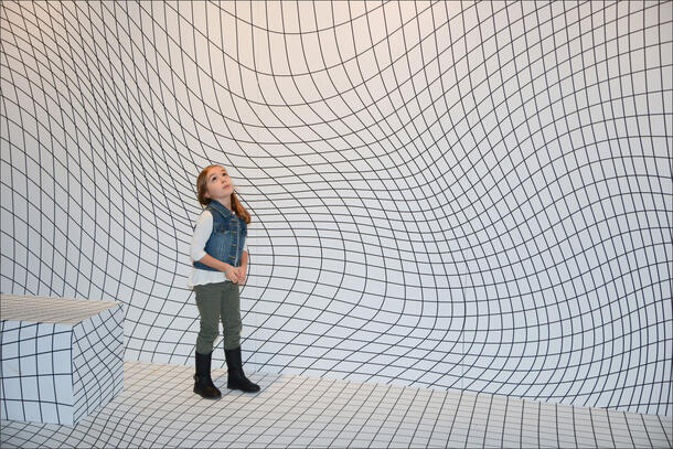 A child walks through a white room with black wavy lines.