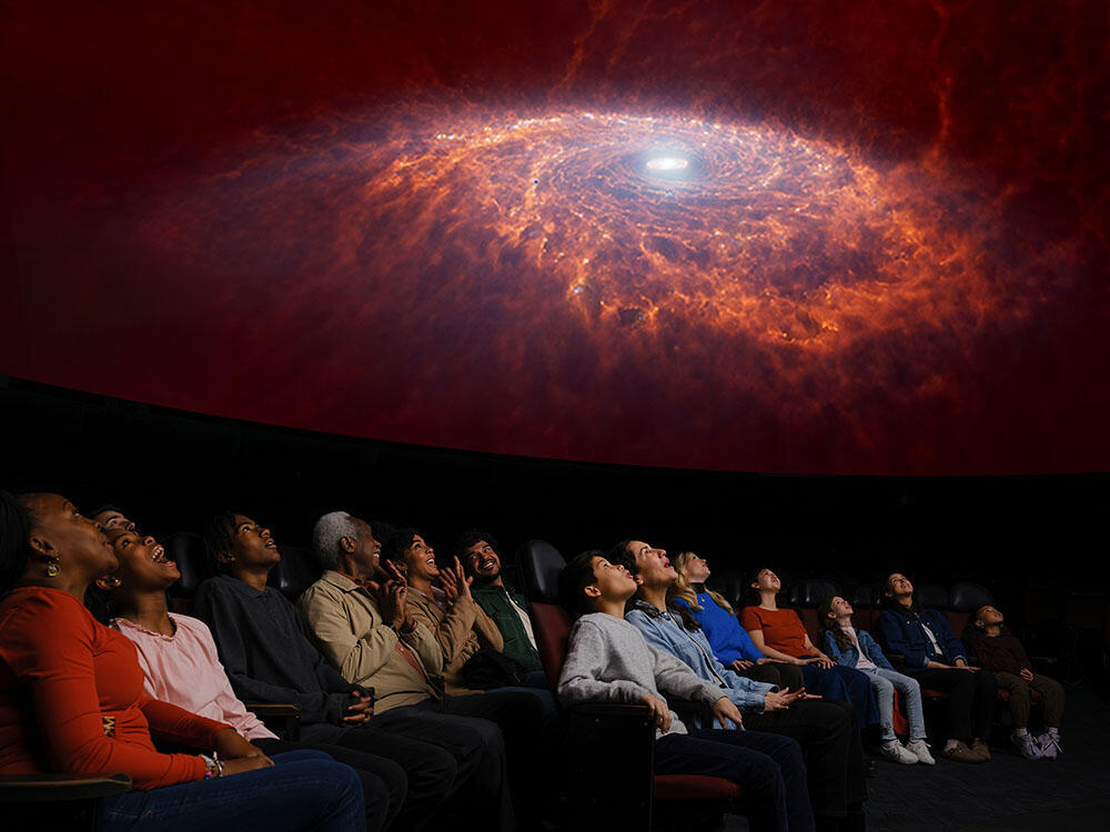 Seated visitors view an overhead projection of space.