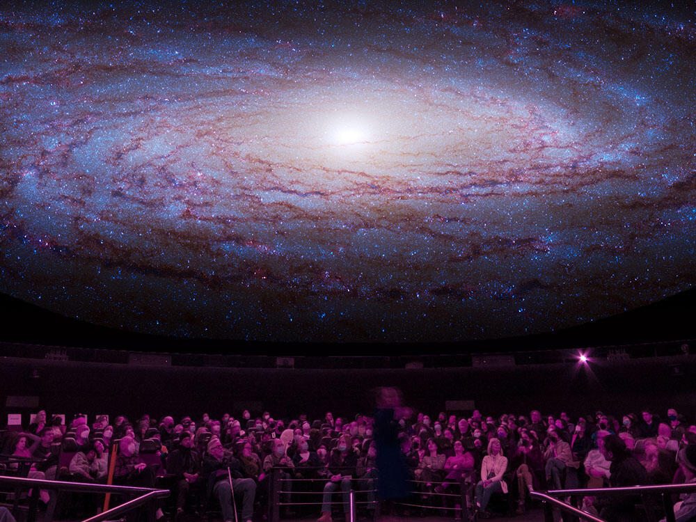 Seated visitors view an overhead projection of images from space inside the Museum's Hayden Planetarium.