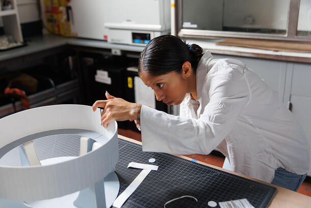 Dani Curlin leans over a work table to construct a model.