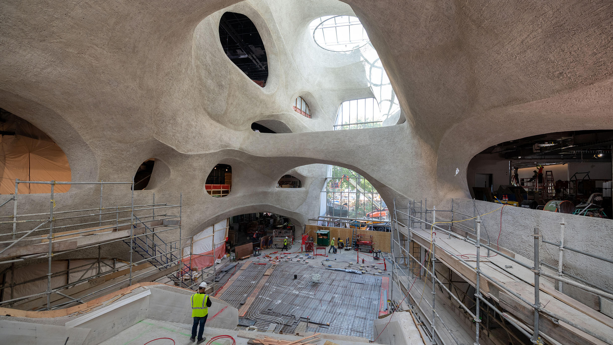 Worker in construction vest and helmet oversees the construction process within the soaring walls of the Gilder Center.