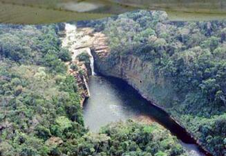 A river at the bottom of a gorge whose steep sides and tops of each side have thick green tree cover.