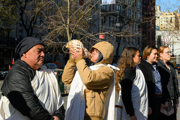Nā Hoa Aloha representative Talon Pōhaku Hundley blows a conch shell at the 77th Street entrance to the Museum as part of the kāhea and komo protocol.