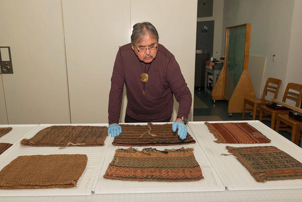 Mr. David Grignon examines a colorful collection of Menominee twined bags during a visit to the Museum's Anthropology Department.