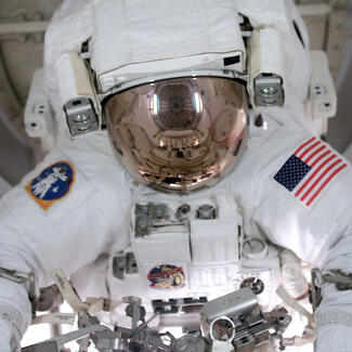 John Herrington is wearing a full space suit inside a space capsule.