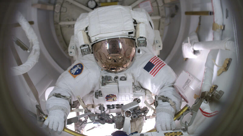 John Herrington is wearing a full space suit inside a space capsule.