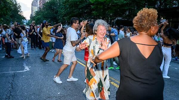 Two women dancing in a lively street festival.