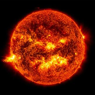An image of the sun, bright burning swirling orange against a black background, with yellow solar flares exploding from its southern hemisphere.