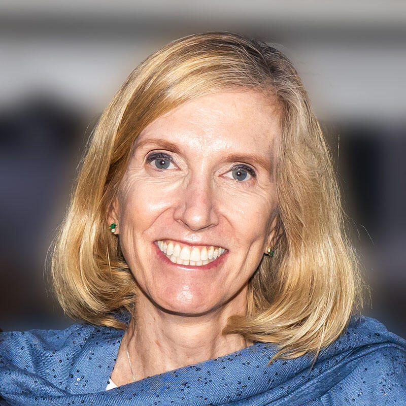 Smiling headshot of Kari Nadeau in front of a plain backdrop.