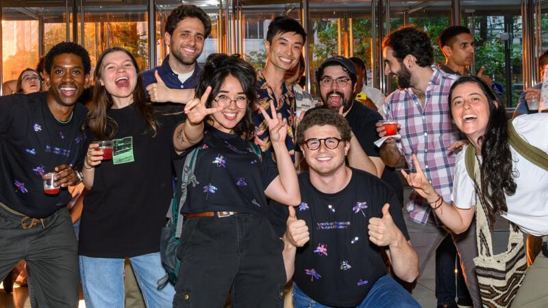 Partygoers gathered in the museum atrium, standing together and smiling at the camera.