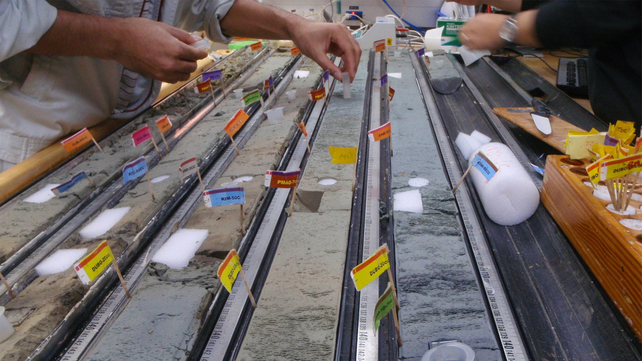 Scientists add identification flags to cylindrical rows of clay taken from the sea floor in the South Pacific Gyre.