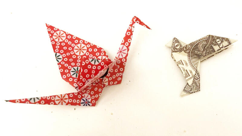 A folded origami crane in a brightly colored, patterned paper (left) and a one dollar bill folded into an origami dove (right).