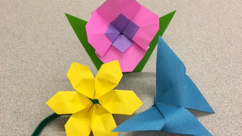 Two colorful origami flowers (one with a stem and one with two leaves) and an origami butterfly.