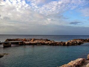 A wall made of large stones in a wide body of water.