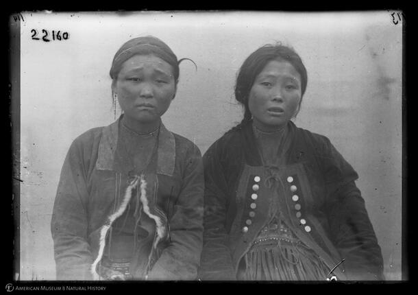 Two Yukoghir girls wearing jackets that tie closed above layers of clothing.