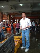 A man at an indoor fish market smiling at the camera.