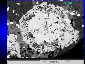 A slide titled "Eclogite" with a specimen magnified to show a large white area specked with black and gray against a larger mottled dark gray area.