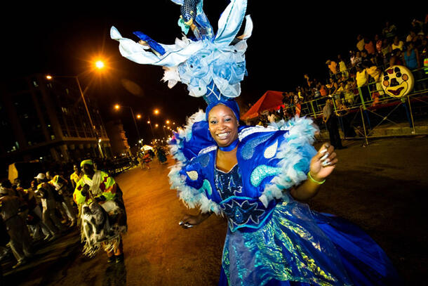 A performer in a ruffled costume dances in the street.