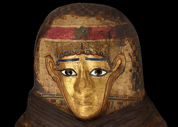 Detail view of the layers of the headdress made from papyrus and linen, topped with a gold-painted face.