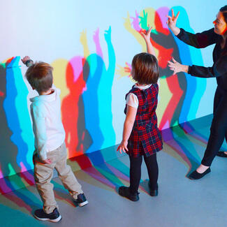 Visitors view colored shadows on a wall in the Nature of Color exhibition.